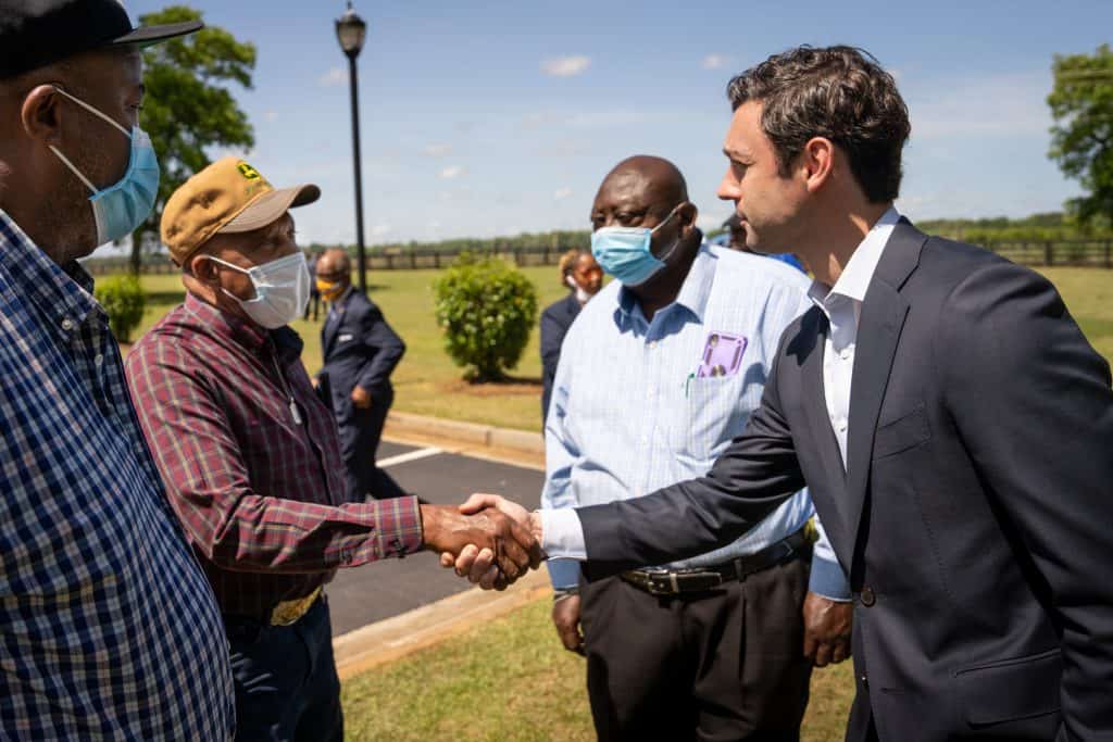 Senator Ossoff shaking hands with a farmer while two others look on outside in Fort Valley, Georgia.