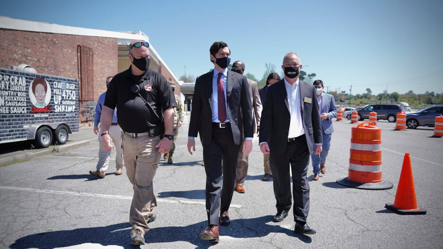 Senator Ossoff walking with officials in a parking lot.